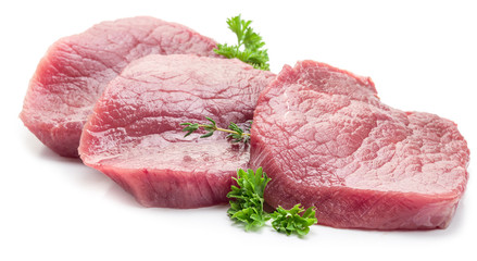 Raw beef steaks with parsley on a white background.