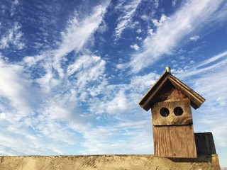 wooden nesting box against cloudy blue sky