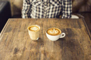 Girl with two different cups of coffee on a wooden table