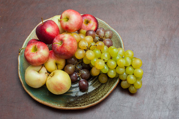 Plate with fresh autumnal fruits, apples and grapes