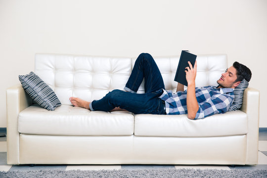 Man lying on the sofa and reading book