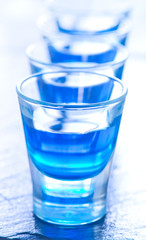 blue alcoholic drink into small glasses
