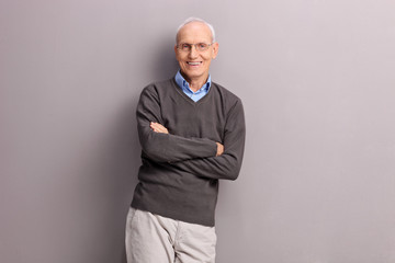 Cheerful senior leaning against a gray wall