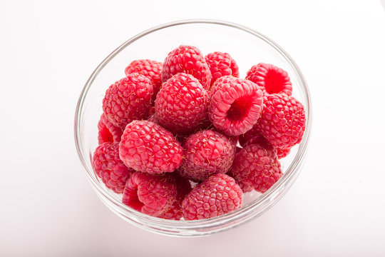 Ripe sweet raspberries in bowl on white