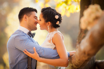 Smiling couple hugging kissing in autumn park. Happy bride and groom in forest, outdoors