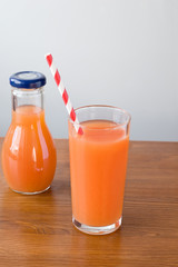 glasses of carrot juice on wooden table on brown background