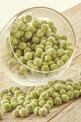 Frozen peas in glass on wooden background