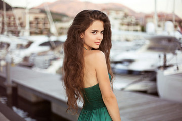 Beautiful young smiling girl with long hair by the yacht at suns