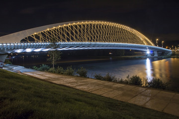 Fototapeta na wymiar Modern lighted bridge in night for cars and trams in Troja, Prague, Czech republic