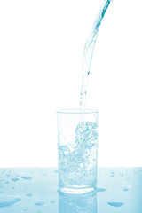 Pouring water from bottle into glass on white background.