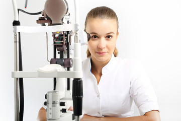 Szpital oddział okulistyki, młoda okulistka siedzi przy maszynie do badania oczu - obrazy, fototapety, plakaty