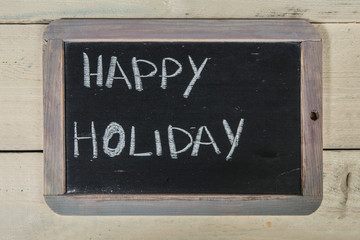 Lavagna con scritta "happy holiday" su sfondo di legno