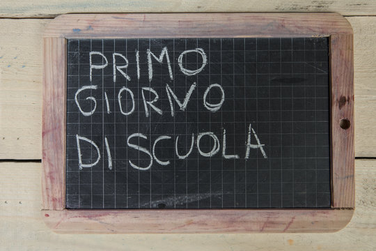lavagna con scritta " primo giorno di scuola su sfondo di legno"