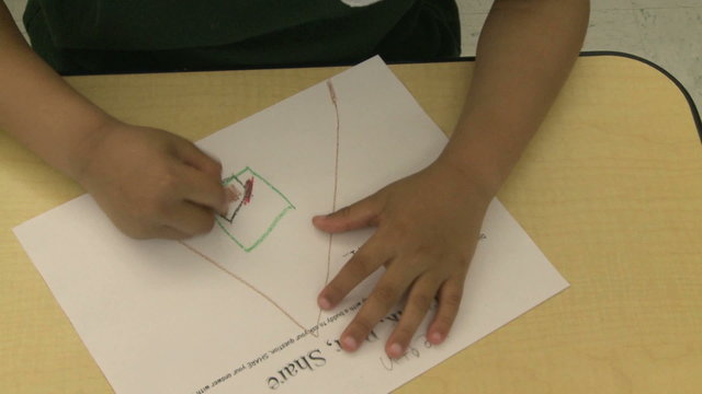Grammar school student drawing with crayon in classroom