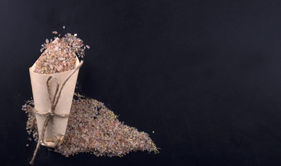 Himalayan salt with spices in a paper bag on a black background.