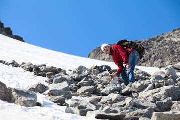 Hiker stepping on sharp stones while climbing the snowy mountain pass