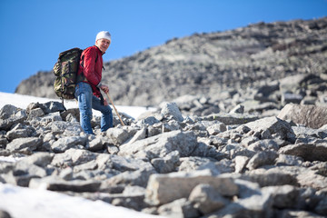 Mountaineer resting after heavy climbing on stony and snowy mountain slope, copy space