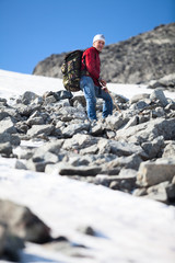 Mature mountaineer resting during heavy climbing, looking down at camera