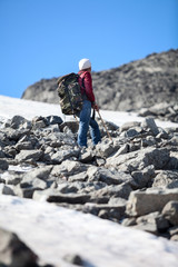 Mature mountaineer resting after heavy climbing on stony mountain slope