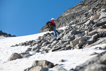 Naklejka premium Senior man a mountaineer resting on the stony steep slope in mountains after difficult climbing