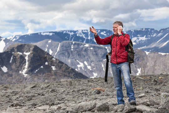 Middle-aged man tells about seen landscape in the mountains, talking on mobile phone