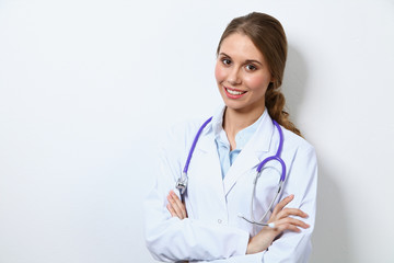 Friendly smiling young female doctor, standing near wall