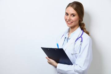 Friendly smiling young female doctor, standing near wall