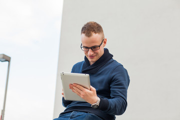 Stylish guy connected on internet with tablet in town. He is happy.