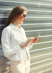 Fashion portrait pretty young woman using smartphone in city