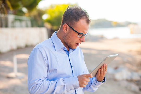 Young tourist under in shirt with mobile tablet pc on a Croatian bech.