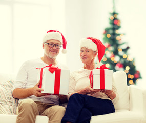 happy senior couple in santa hats with gift boxes
