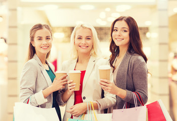 young women with shopping bags and coffee in mall