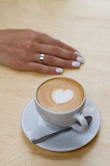 Women's and men's hands with wedding rings with cup of coffee
