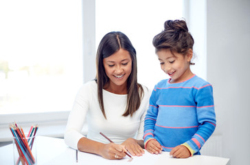 happy mother and daughter drawing with pencils