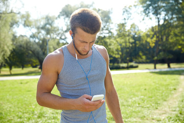 young man with earphones and smartphone at park