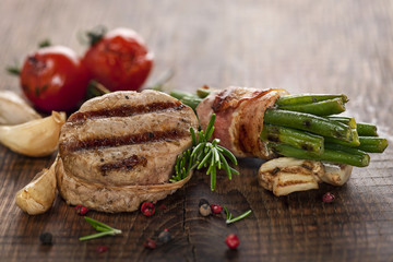 Gegrillte Schweinemedaillons an Gemüse auf rustikalem Holzbrett