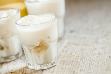 Fresh homemade banana yogurt in glass on old wooden table, selec