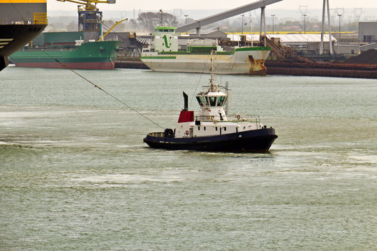 Tugboat towing ship in harbor