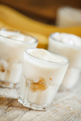 Fresh homemade banana yogurt in glass on old wooden table, selec