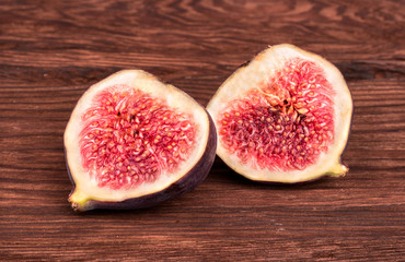 Two halves of sliced fresh figs on a wooden background