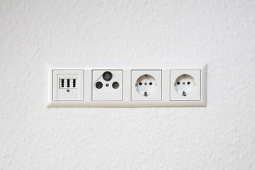 Electrical outlet, phone and antenna socket on room wall
