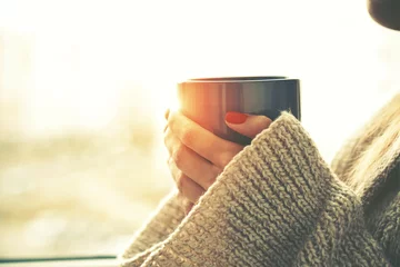 Foto op Aluminium handen met warme kop koffie of thee in de ochtendzon © Ivan Kruk