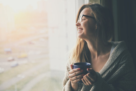 cheerful girl drinking coffee or tea in morning sunlight 