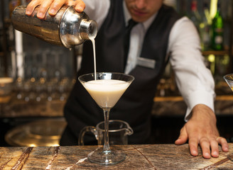 Barman at work, preparing cocktails. pouring pina colada to cocktail glass. concept about service and beverages.