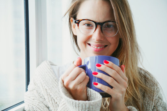 cheerful girl drinking coffee or tea in morning sunlight