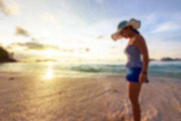 Blurred image for background, Tourist woman in a swimsuit watching sunrise on the beach and sea at Miang island in Mu Koh Similan National Park, Phang Nga Province, Thailand