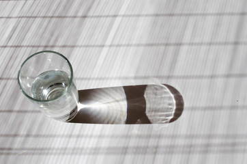 Glass of water lightened with sun on a white table