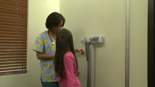 Nurse measures young female patient's height