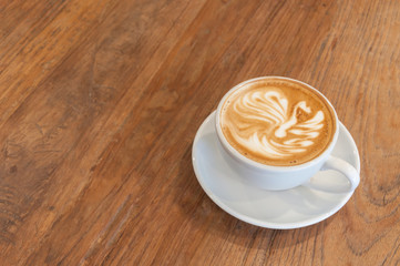 Hot cafe latte with latte art on wooden table