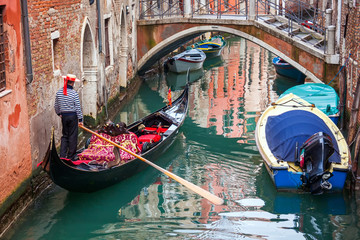 man in gondola in narrow canal with bridge Venice, Italy, Europe